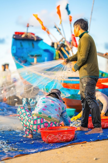 背面図 日の出または日没時に網を投げる漁師 伝統的な漁師が漁網を準備する