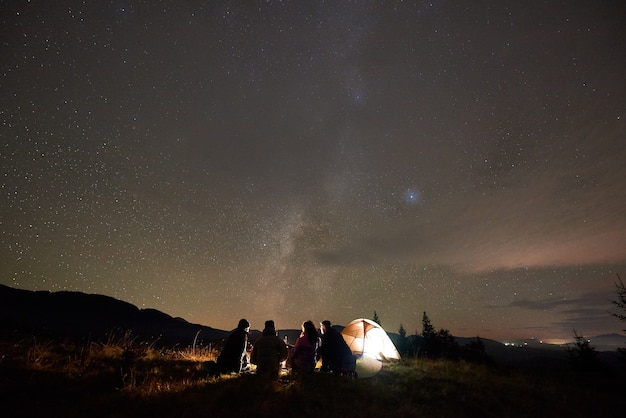 Back view of five people sitting at tourist tent