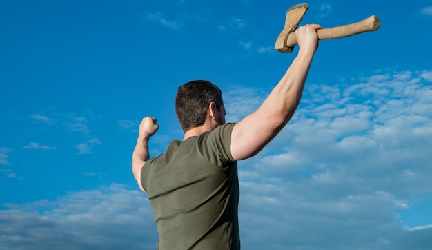 Back view of free man with axe man hold ax brutal man on sky background