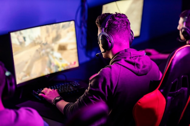 Back view of gamers playing online game tournament at gaming room