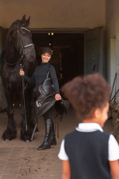 Photo back view girl learning to ride horse