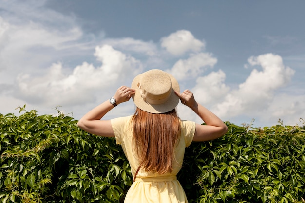 Foto ragazza posteriore di vista che posa con la pianta