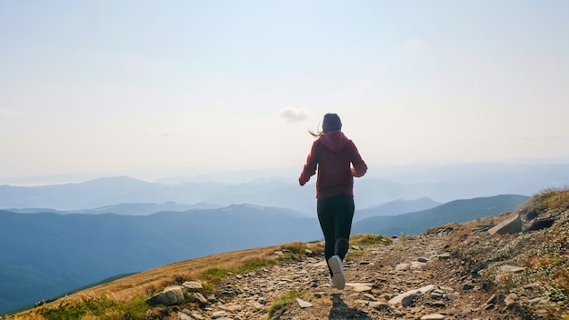 Back view of girl running on the mountain valley.