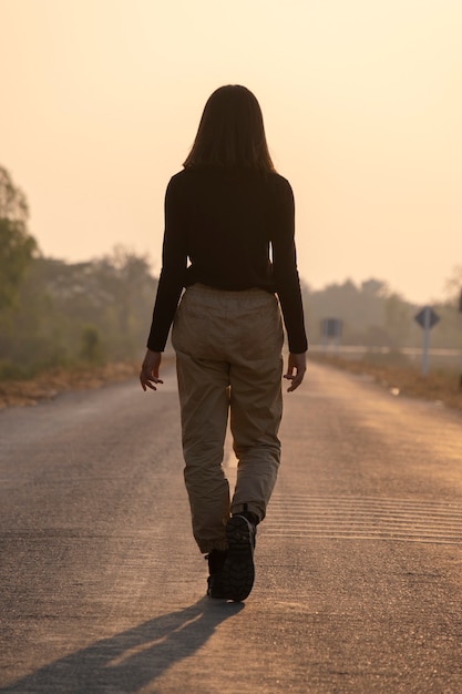 The back view of a girl walking a long road alone