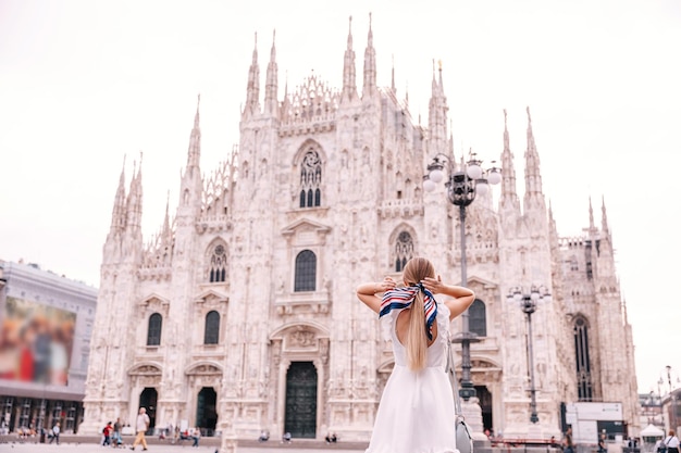 Back view of a girl in a white dress straightens her headscarf a