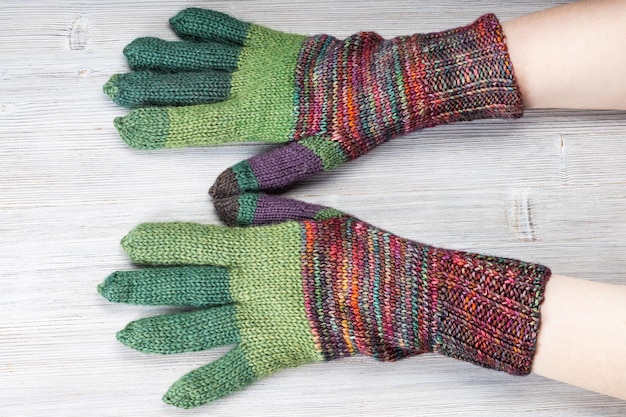 Back view of hands in knitted gloves on gray