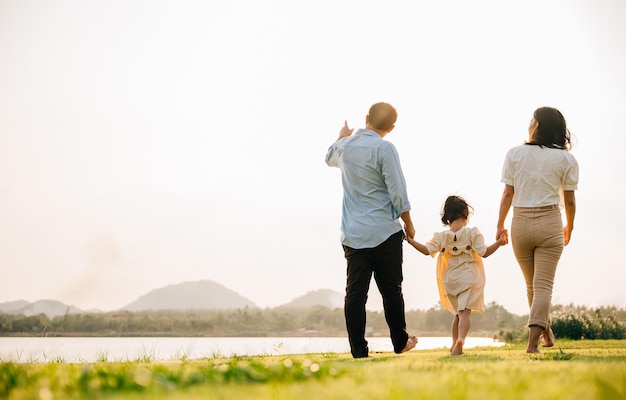 Back view of Happy Asian family walking and playing together in a scenic garden