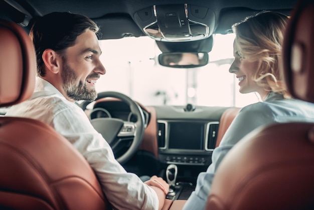 Back view of of happy couple talking together while sitting in new car