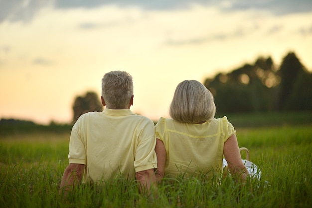 Back view Happy elderly couple resting at sunset