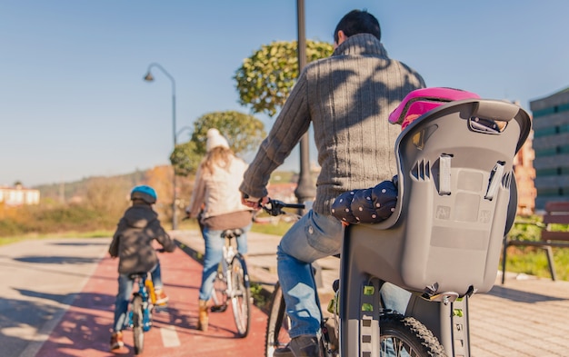 Back view of happy family with children riding bicycles by the nature on a sunny winter day