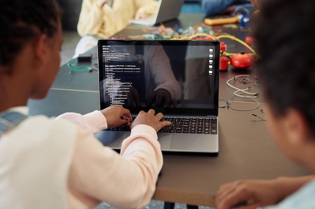 Photo back view of kids using laptop in engineering class and programming robots copy space