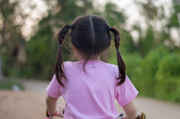 Photo back view of little asian girl smiling with her bicycle selective focus.