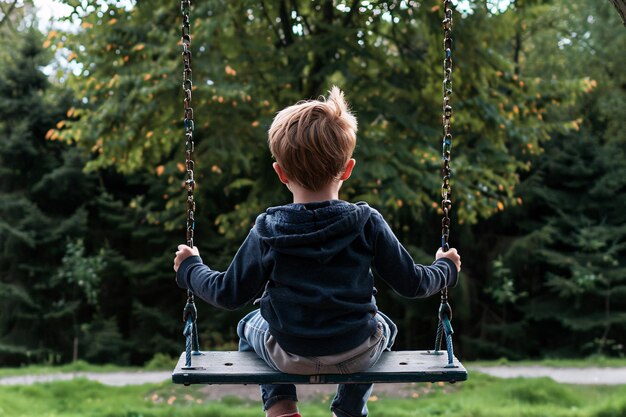 公園で振り回されている小さな男の子の後ろの景色