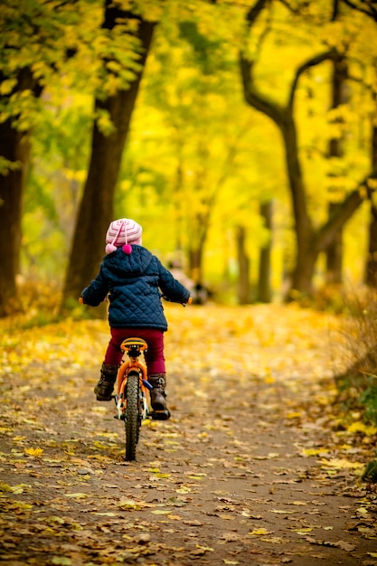 Back view of Little child in blue coat riding a bicycle.