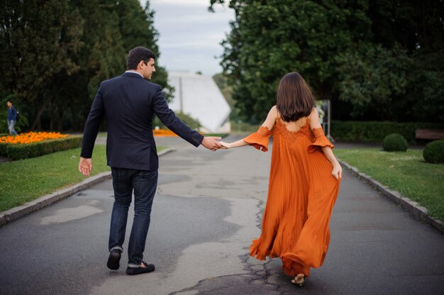 Back view of love couple holding hands and walking on the road