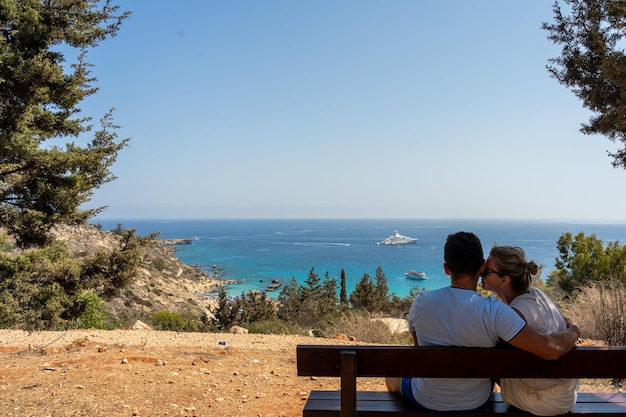 Back view of lovely couple relax on bench sitting near the sea Wanderlust