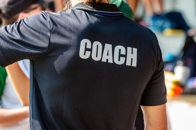 Back view of a male coach in black COACH shirt