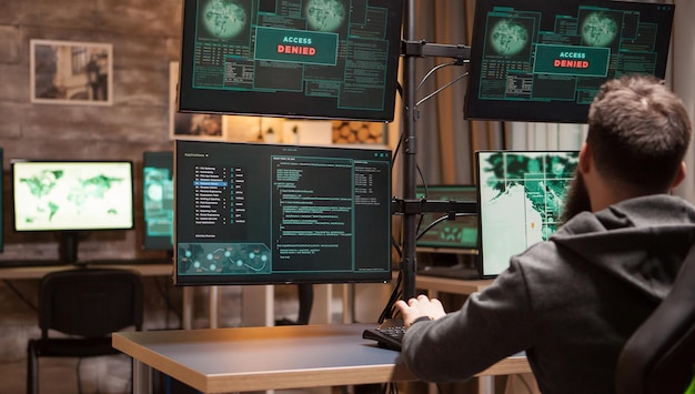 男性のハッカーの背面図は、マルウェアを仕掛けようとしているときにアクセスが拒否されます。