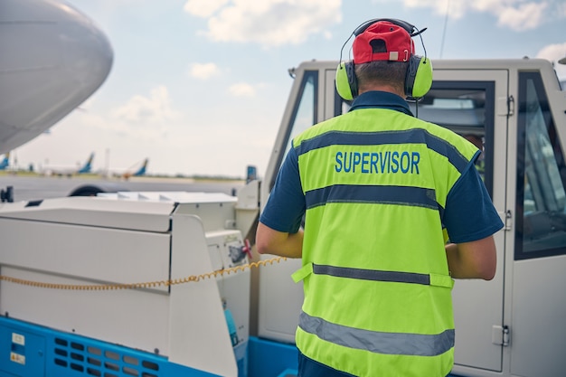 Back view of a male worker in a safety vest looking into a driver compartment