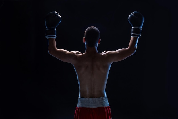 Back view of man boxer with raised hands in victory gesture concept of hard sport glory and success