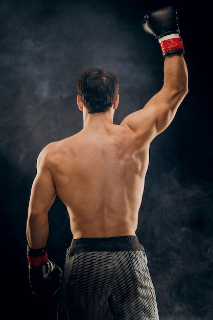 Back view of man boxer with raised hands in victory gesture Concept of hard sport glory and success