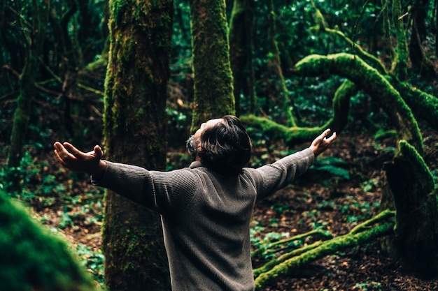 Back view of man enjoying and feeling the forest woods around him people and nature care love environment stop deforestation travel tourist in the green musk woods scenic place destination