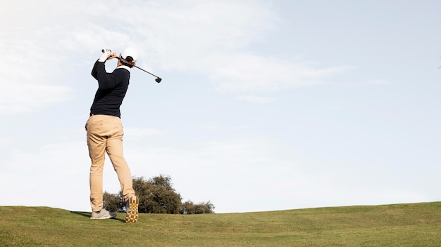 Vista posteriore dell'uomo che colpisce la pallina da golf sul campo