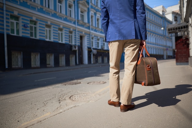 Back view of a man in a jacket and hat on the street