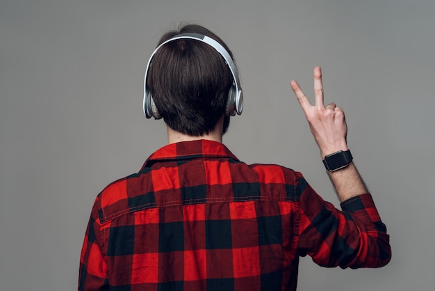 Back view. Man listening to music with headphones