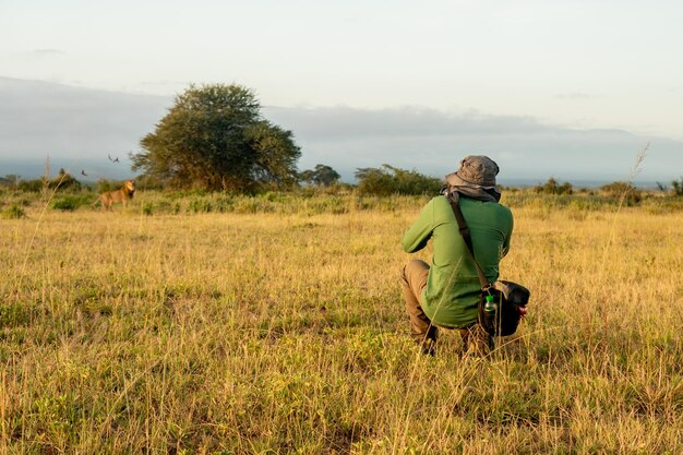 Foto una vista posteriore di un uomo che fotografa un leone nei cespugli pericoloso safari africano caccia fotografica turistica in safari in namibia