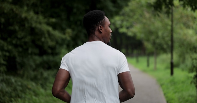 Back view of man running in sportswear outdoor. african\
american man exercising outdoors, running in city park. fitness,\
active and healthy lifestyle concept.