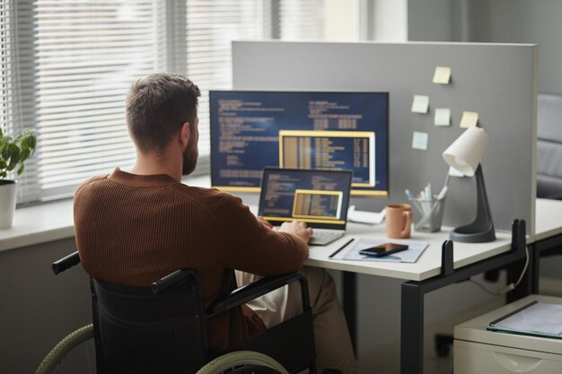 Back View Man with Disability as It Professional Using Computer