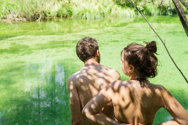 Back view of man and woman young friends enjoying on the river