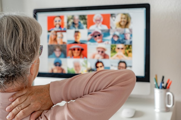 Back view of mature caucasian woman tired with neck pain after\
overwork activity stressed female busy at graphic computer smart\
work concept