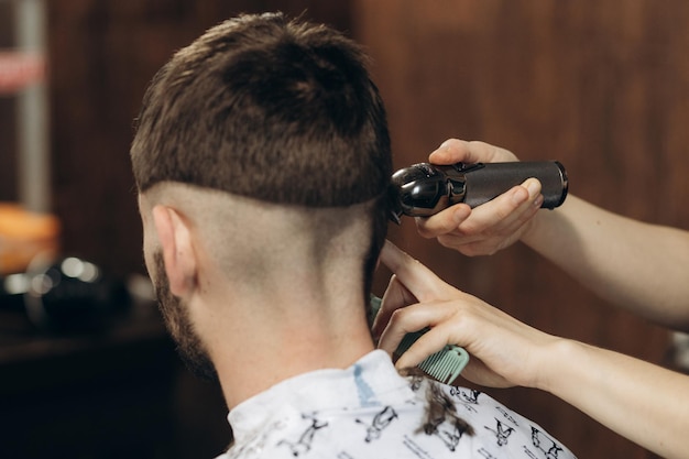 Back view of Men in beauty salon Men's haircut in a barbershop Professional hairdresser uses a hair clipper for fringing hair