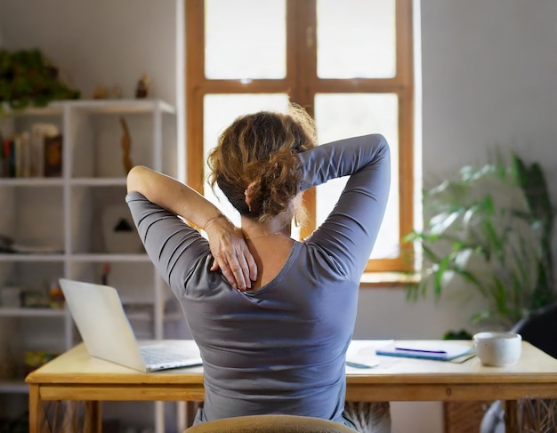 Foto vista posteriore di una persona di mezza età in una stanza di studio che mantiene una postura ergonomica corretta che affronta dis...