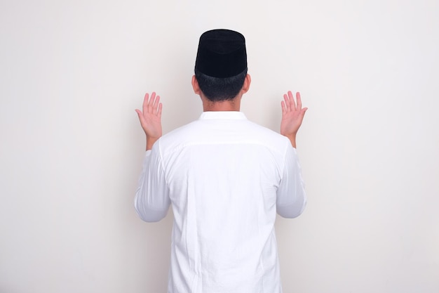 Photo back view of moslem man doing praying gesture