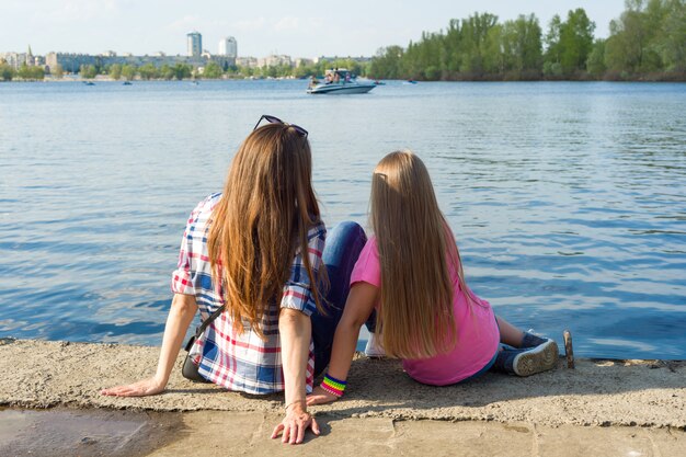 Back view mother and daughter watching the water