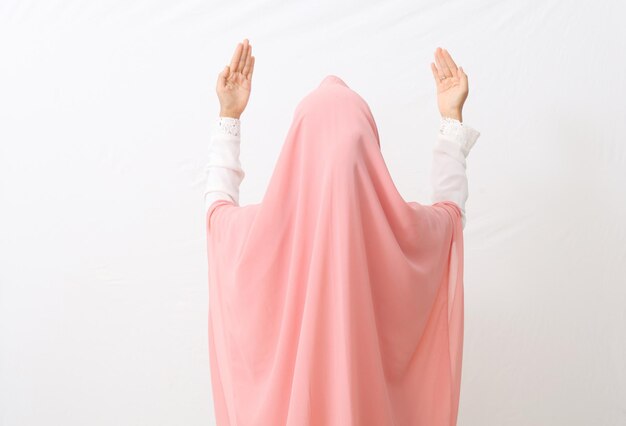 Back view of a muslim woman wearing a veil or hijab praying.
isolated on white background with copy space