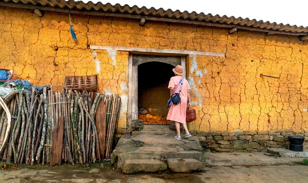 写真 建物 の 入り口 に 立っ て いる ピンク の 服 を 着 た 女性 の 後ろ の 姿