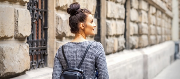Вид сзади молодой женщины с рюкзаком прогулки в европейском городе