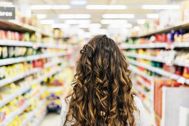 Вид сзади красивой женщины, покупая еду в супермаркете. концепция рынка продуктов питания.