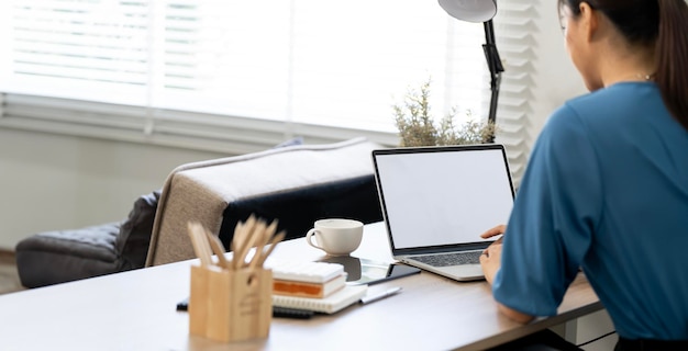 写真 ホームオフィスのノートパソコンを使用するビジネス女性のバックビュー ⁇ 白い画面のモックアップ