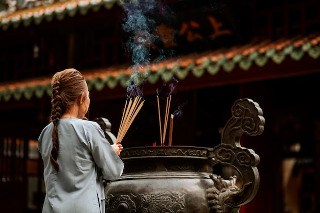 写真 燃える線香と寺院で宗教的な女性の背面図