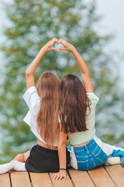 写真 霧と山の背景に高い山のテラスに座っている若い女の子の後ろの景色