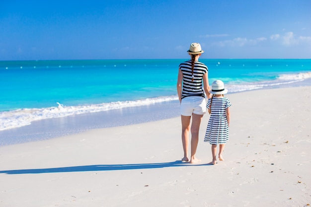 若い母親とカリブ海のビーチで小さな娘の背面図