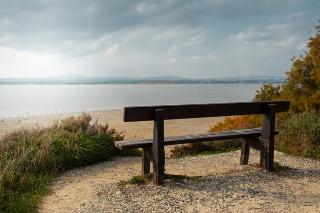 Back view of old wooden bench on coast of lake