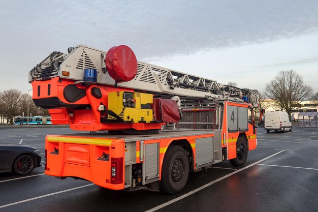 Back view of an orange fire truck standing in a large parking lot