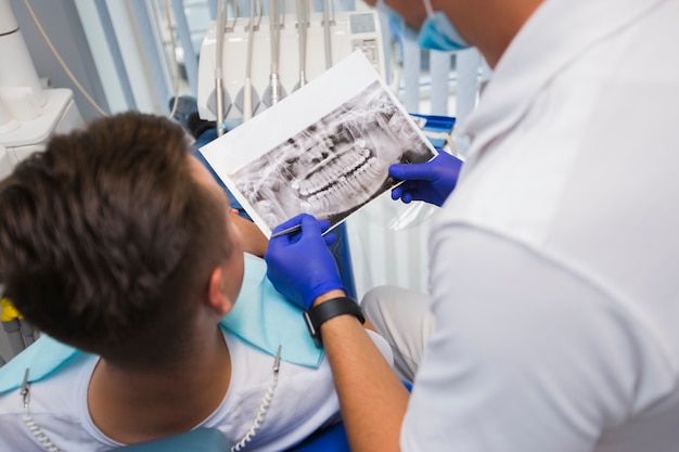 Punto di vista posteriore del paziente e del dentista che esaminano radiografia