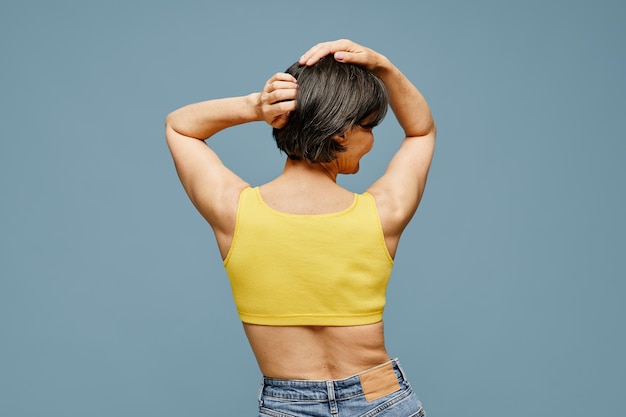 Back view portrait of carefree mature woman posing against pastel blue background copy space